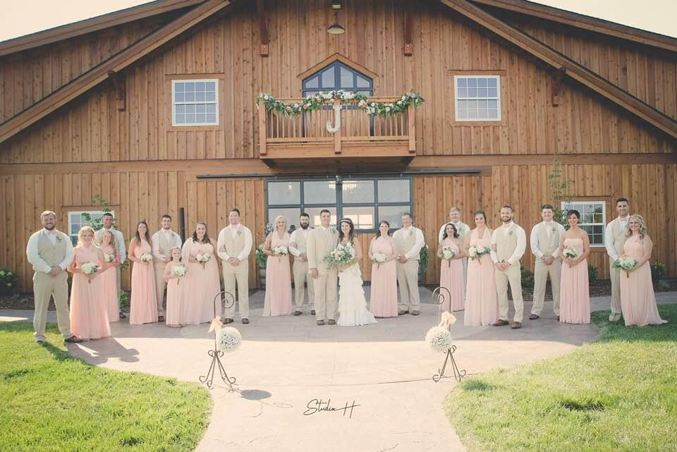 Wedding party poses outside The Homeplace for Hayden Johnston's wedding in matching outfits pink and beige